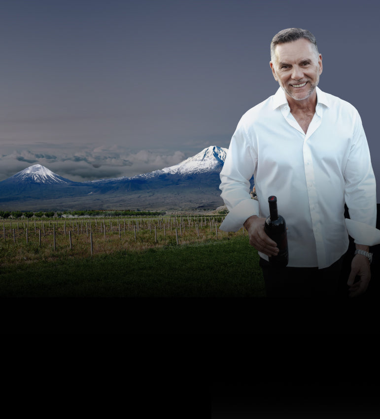 Man holding a bottle in front of a scenic mountain landscape