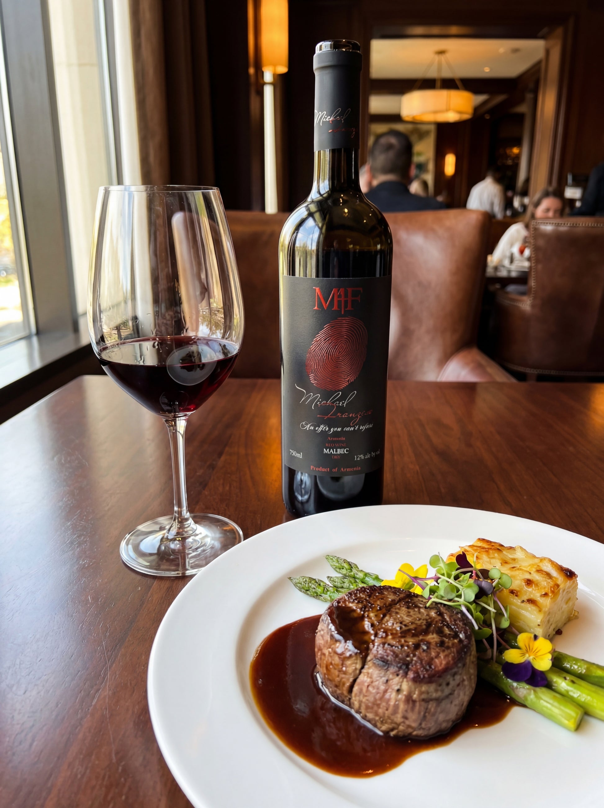 Steak dish with wine bottle and glass on a table in a restaurant setting